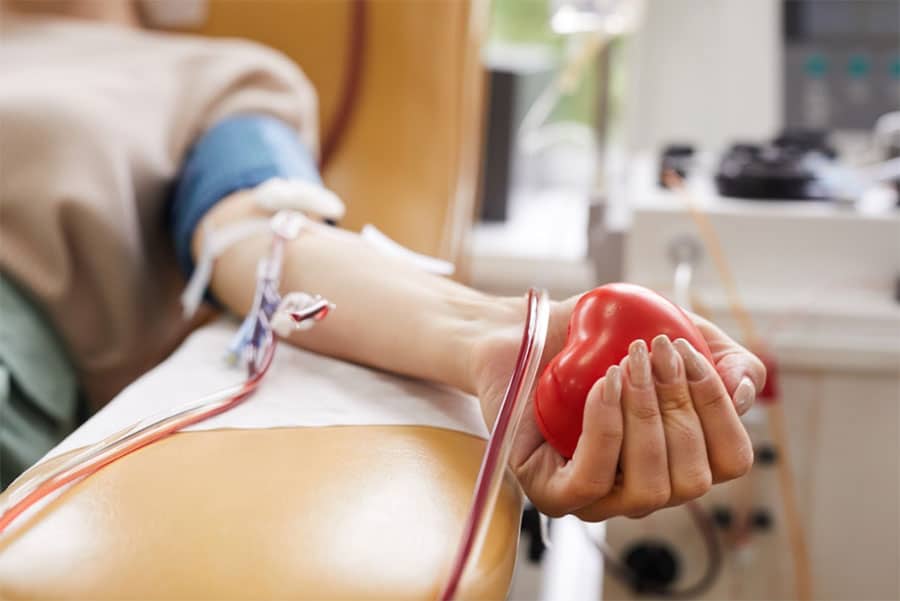 A donor squeezing a heart-shaped stress ball while giving blood