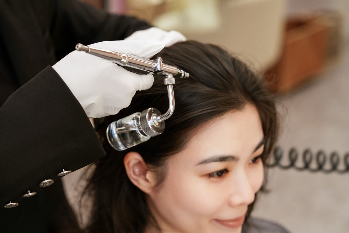 A TrichoLab specialist airbrushing a treatment onto a client’s scalp