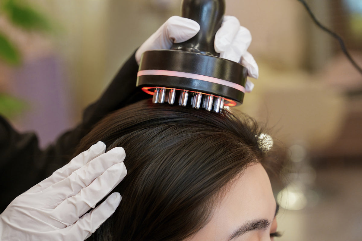 A TrichoLab specialist using a massage device on a client’s scalp