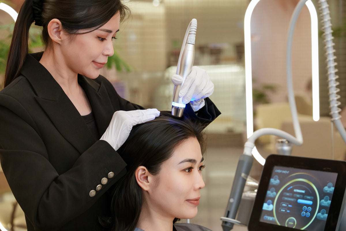 A TrichoLab specialist treating a client’s scalp with a handheld LDM device