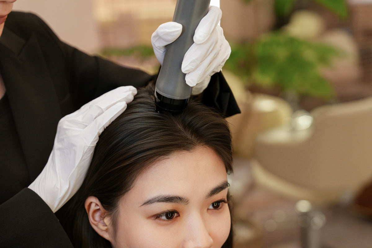 A TrichoLab specialist treating a client’s scalp with a handheld device