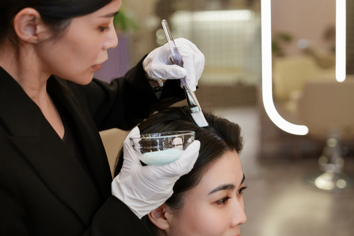 A TrichoLab specialist brushing Moringa Seed Oil Treatment onto a client's scalp