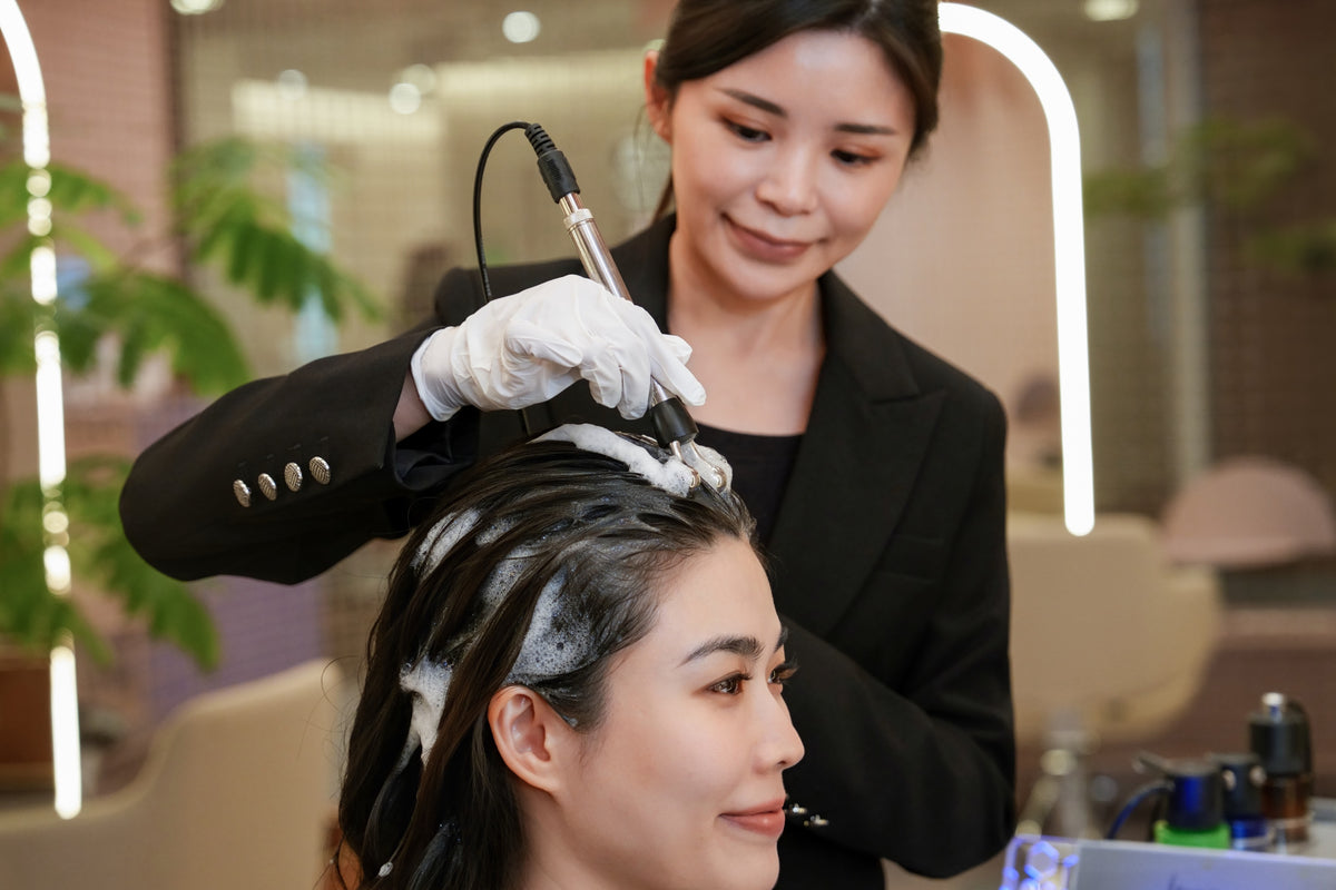 A TrichoLab specialist treating a client’s scalp with a handheld device