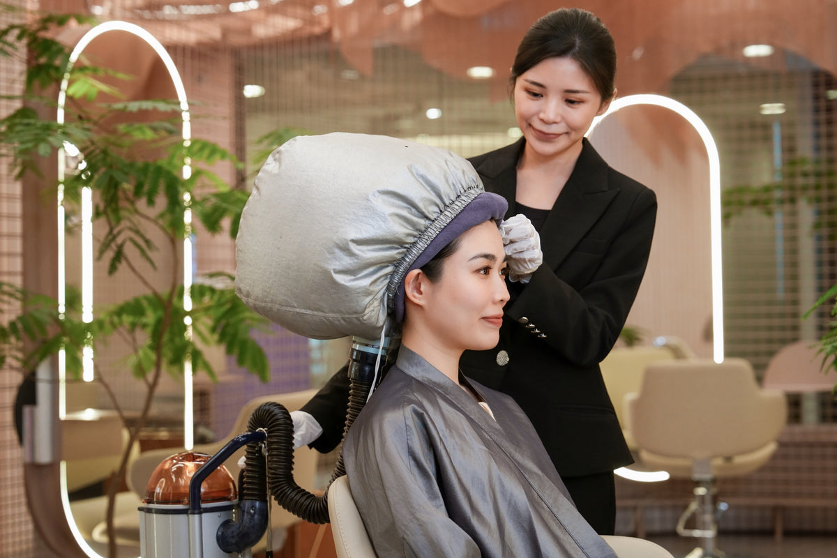 A client relaxing under a hair steamer during the Caviar Treatment at TrichoLab