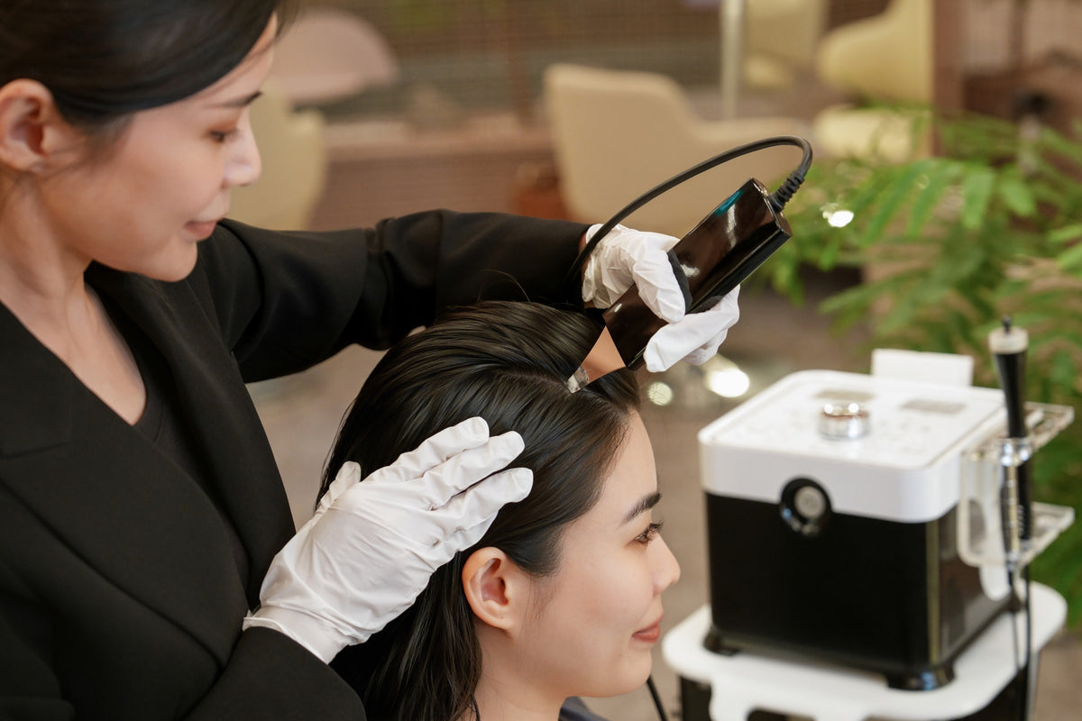 A TrichoLab specialist treating a client’s scalp with a handheld device