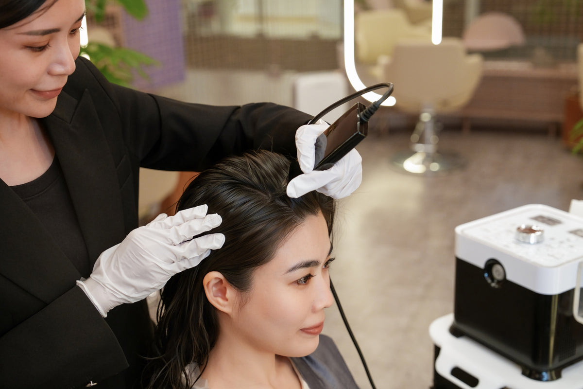 A TrichoLab specialist treating a client’s scalp with a handheld device