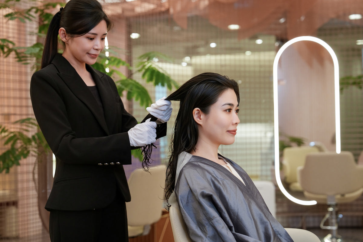 A TrichoLab stylist working a conditioning treatment through a client's lengths
