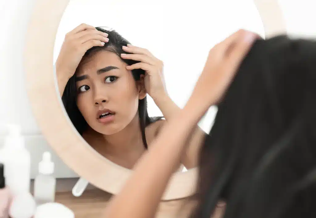 Woman examining her scalp in the mirror
