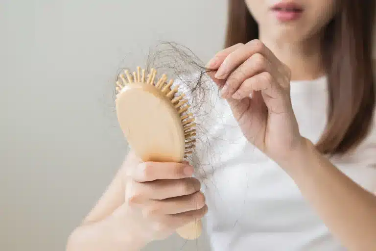 Woman looking at hair shed on brush